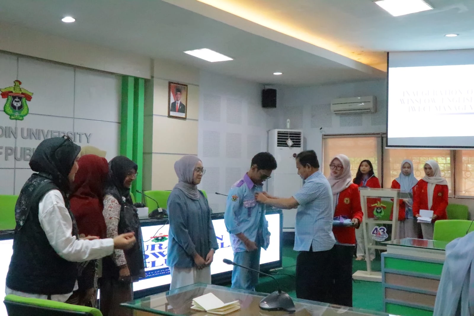 Dekan FKM Universitas Hasanuddin, Prof. Sukri Palutturi, SKM, M.Kes., MSc.PH., Ph.D., secara simbolis menyematkan atribut organisasi kepada Ketua Winslow English Club masa bakti 2025–2026 dalam prosesi pelantikan di Ruang Prof. Dr. Nur Nasry Noor, MPH, sebagai penanda resmi dimulainya kepengurusan baru yang siap memperkuat budaya akademik berbahasa Inggris di lingkungan fakultas.